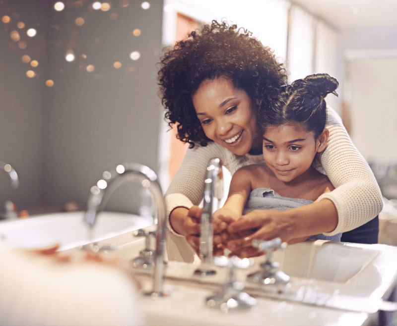 A mother and daughter washing their hands at the bathroom sink.