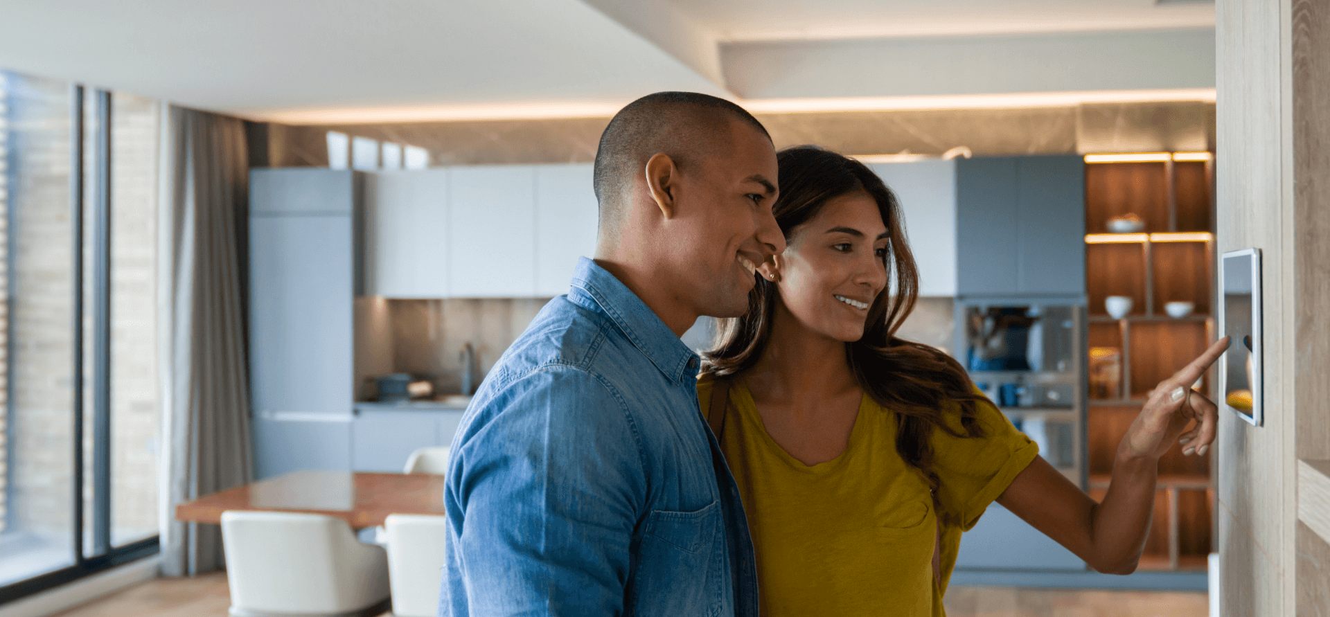 Pareja feliz que controla las características de su casa mediante un sistema automatizado en una tablet.