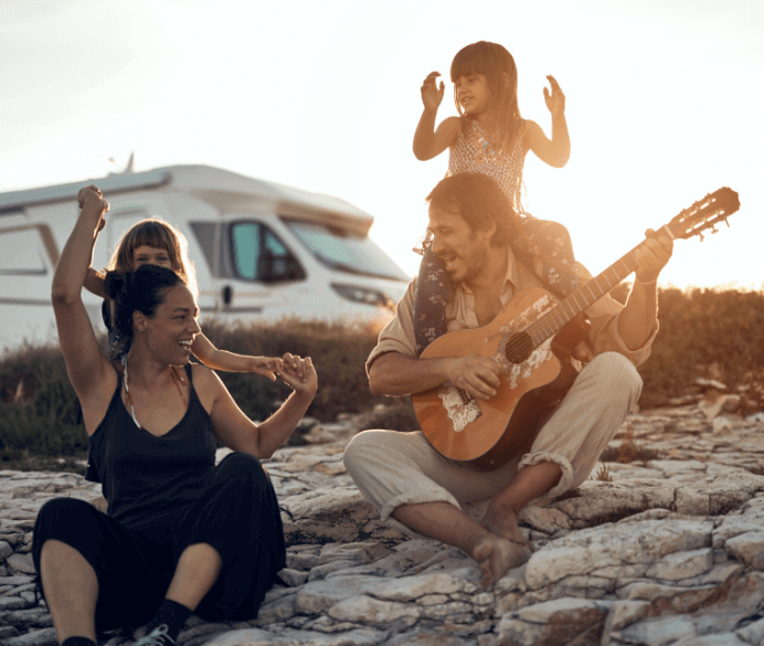 Familia que disfruta de unas vacaciones de verano cantando y tocando la guitarra.