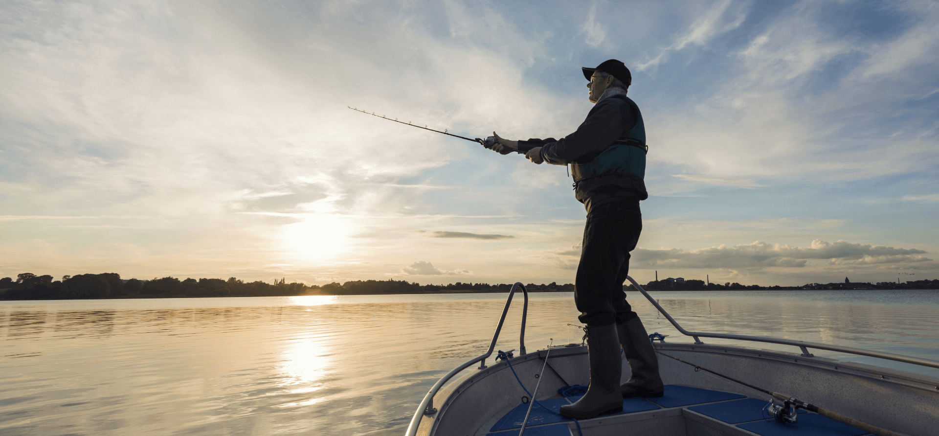 Pescador echando el sedal desde su bote en un mar llano y tranquilo.