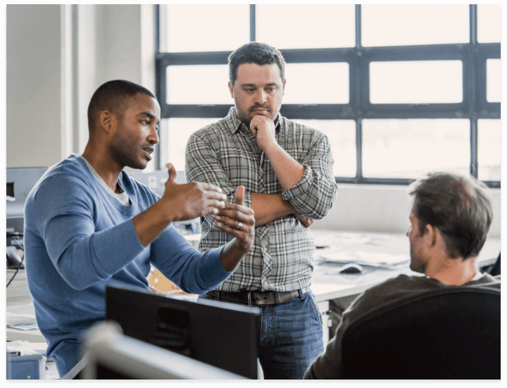 Three colleagues sharing ideas at a workplace.