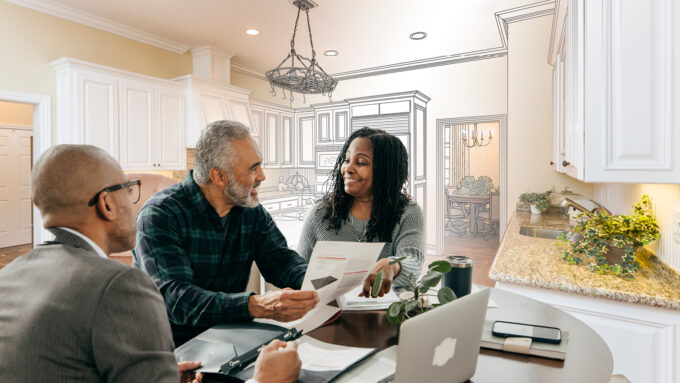 Photo of a contractor offering home improvement financing to a couple sitting at their kitchen table.