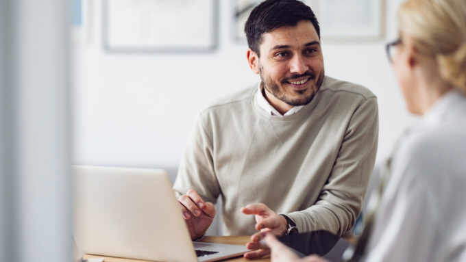 A dealer sits across a desk from a customer providing information about financing.