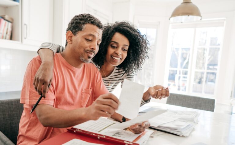 A couple sits together at a kitchen counter planning tax season home improvements.
